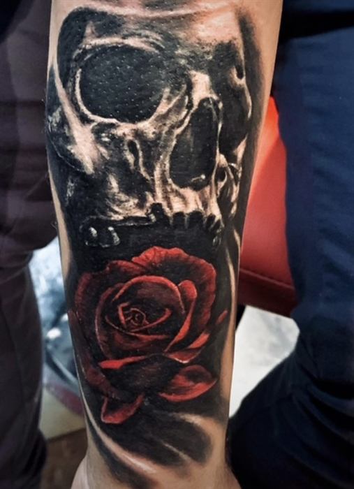 Skull with a red rose on the forearm