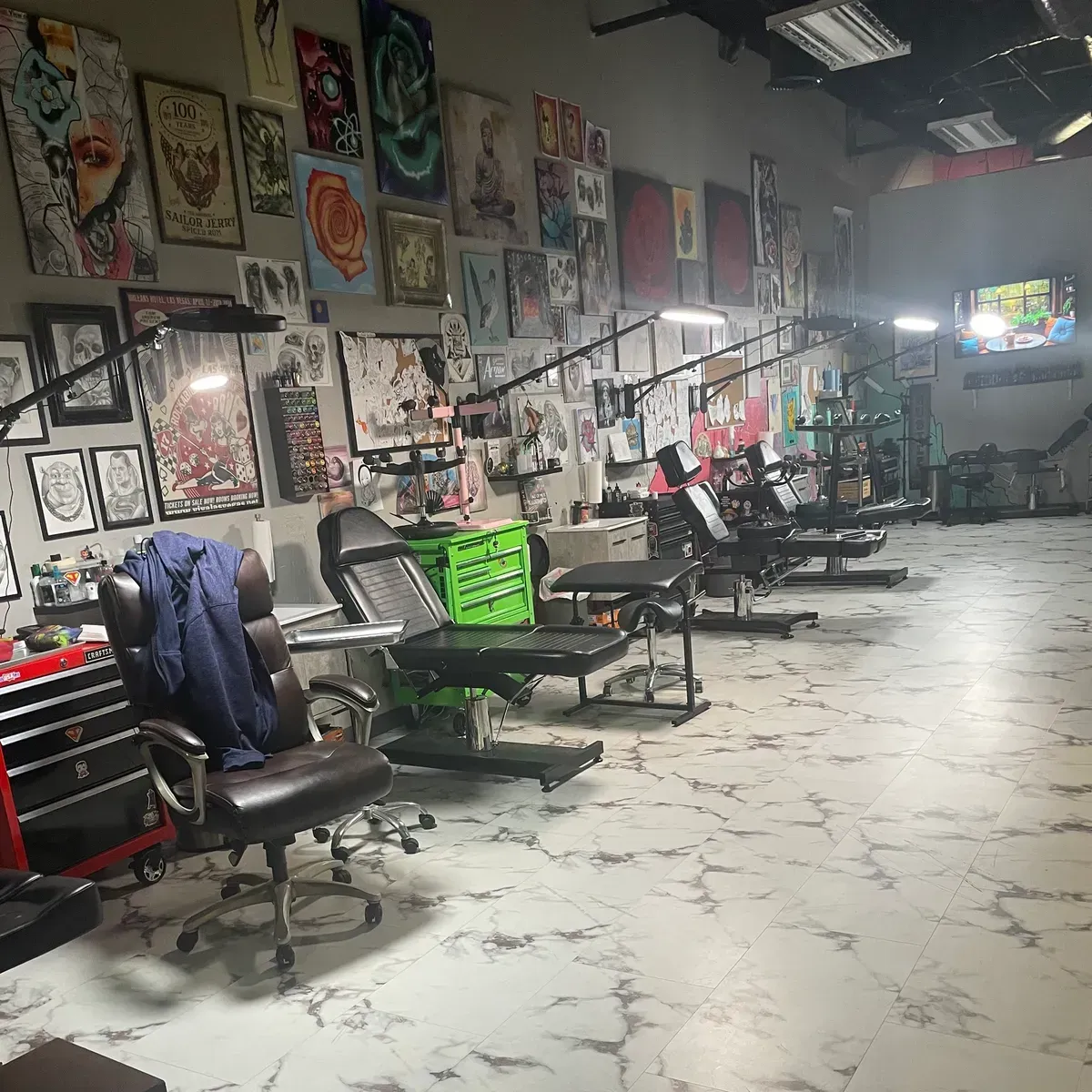 The Affinity Ink studio floor: a row of tattoo stations under flash art covering the walls